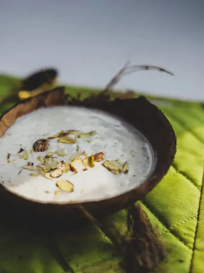 A simple, elegant Indian dessert, perhaps a payasam or kheer, served in a coconut shell. Presentation is as important as taste.