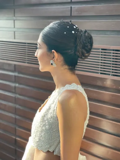 A side profile of the pearl-studded bun, showing the careful placement of each pearl to create a starry effect.