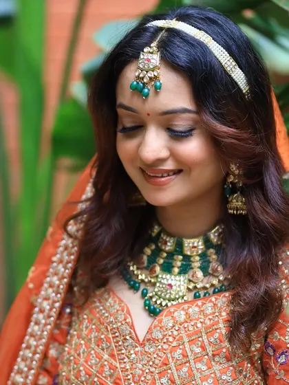 A royal Indian bride look with soft, glowing makeup and a beautiful orange lehenga.
