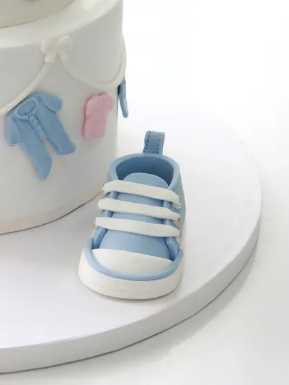 A matching handcrafted blue fondant baby shoe, showcasing the intricate detail of the laces and stitching.
