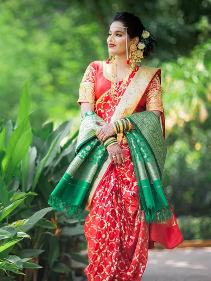 A full-length portrait of a bride in her red and green Paithani saree, showcasing the traditional Maharashtrian bridal look.
