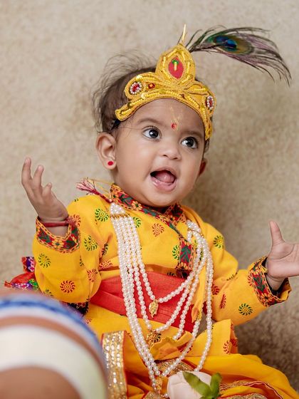 This little Krishna is full of expression, with his hands up and a big, happy shout. These are the moments that truly show a child's personality.