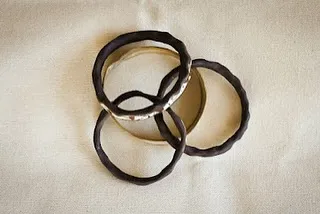 A set of interlocking ceramic bangles with a dark, textured glaze. They make a lovely sound when they move together.