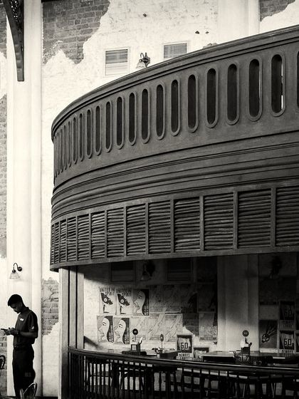 The massive, curved balcony structure overhangs a smaller bar area below, showcasing the complex, multi-level design.