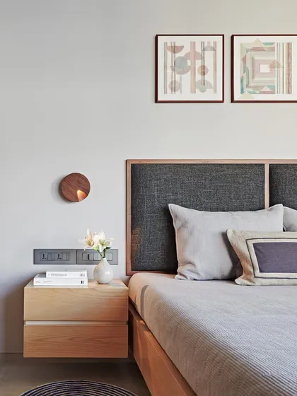 A floating wooden nightstand and a textured fabric headboard create a sense of understated elegance in this bedroom. The soft, neutral finishes and minimalist decor contribute to a timeless and calming interior.