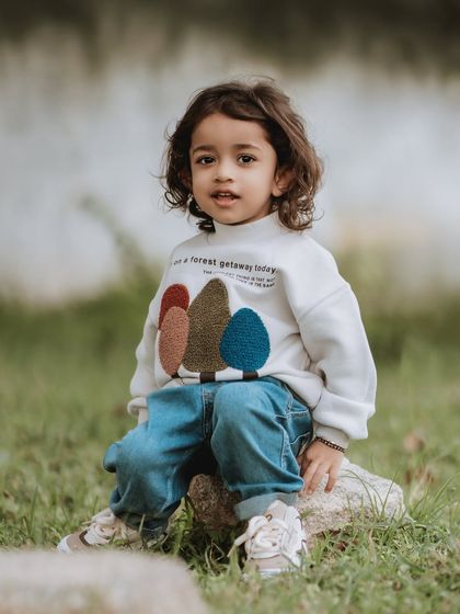 A portrait of a handsome little boy with beautiful curly hair, taken during an outdoor session.