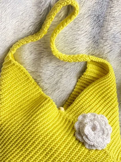 A flat lay of the sunshine yellow crochet bag. It's made with 100% cotton yarn and is a perfect accessory for autumn days or a summer outing.