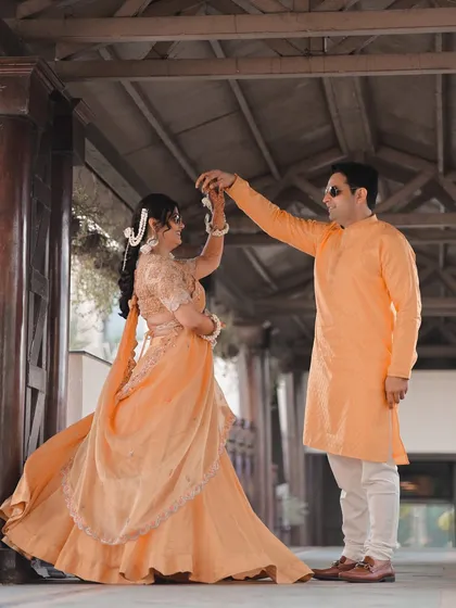 The couple shares a dance, their pastel-colored outfits glowing in the soft light.