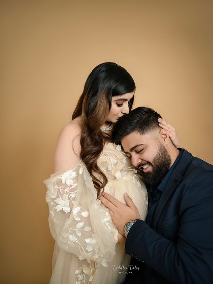 A tender embrace. The father-to-be gently holds the mother and her bump, a beautiful expression of his love and protective instinct.