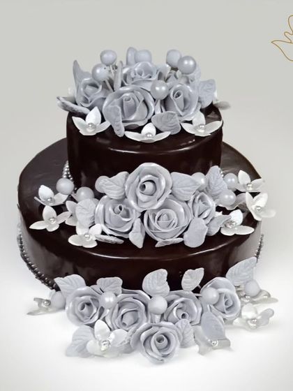 An elegant and decadent two-tier chocolate cake. The rich, glossy chocolate ganache is beautifully contrasted with intricate, handcrafted silver sugar roses, perfect for a sophisticated anniversary or birthday.