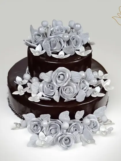 A dramatic and elegant two-tier chocolate cake, adorned with beautiful silver sugar roses. This stunning creation is perfect for a glamorous wedding or anniversary celebration.