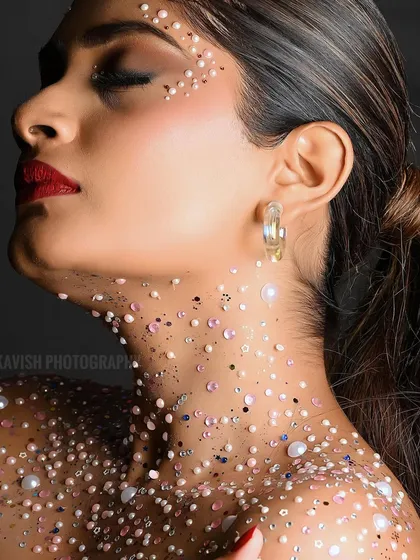 An artistic beauty portrait with a focus on creative makeup, featuring pearls and glitter on the skin for a high-fashion effect.