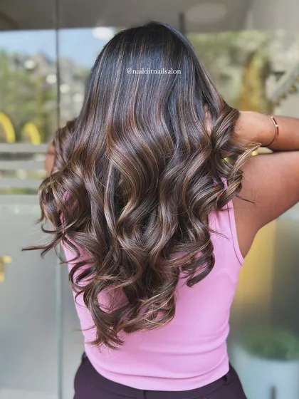This angle captures the light reflecting off the smooth, wavy hair, emphasizing the shine and health of the strands after coloring. The highlights provide depth and make the hair appear fuller.