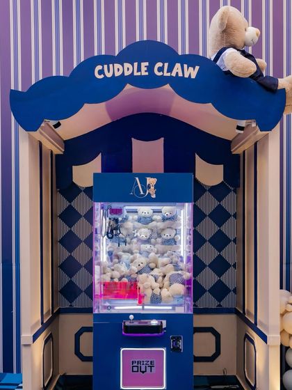 An interactive "Cuddle Claw" machine filled with small teddy bears, providing a fun, on-theme activity and party favor for the children.