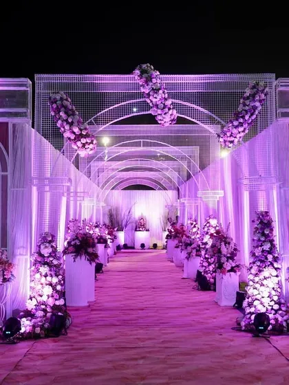 We design pathways that build anticipation and wonder. This stunning floral walkway, illuminated in a soft purple glow, guided guests through a tunnel of blossoms, setting a romantic and enchanting tone for the evening.