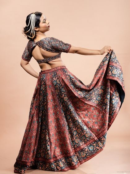 A full-length shot of the model in a printed lehenga, showing the flow and design of the skirt and the stylish open-back blouse. This is a key shot for ethnic wear catalogues.