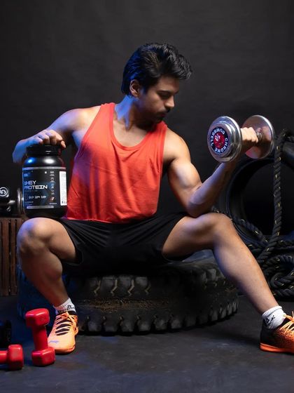 A variation of the dumbbell curl shot, this time with the model holding the whey protein container. This reinforces the brand association with strength training exercises.