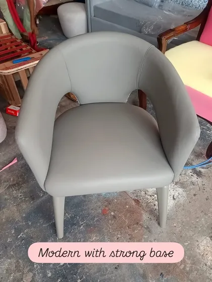 This modern dining chair features a strong base and a comfortable, curved backrest with a cutout detail. The smooth grey upholstery makes it a versatile piece that can fit into many different interior styles.