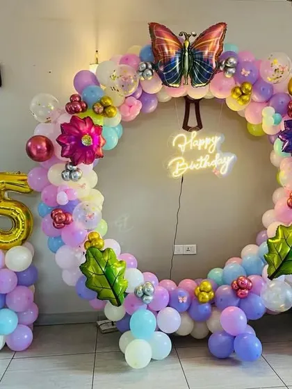 This butterfly garden theme is perfect for a whimsical birthday party. I created a full balloon ring in pastel colors, decorated with flower and butterfly foil balloons, and a 'Happy Birthday' neon sign.