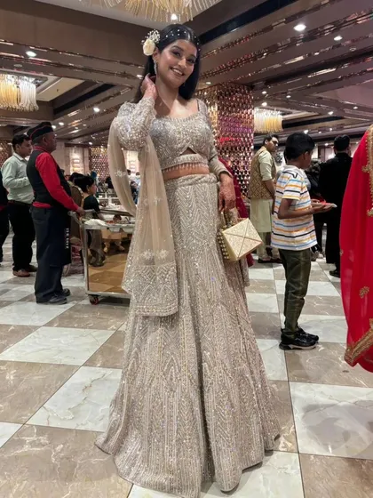 This happy client is all smiles in a shimmering silver-grey lehenga. It's a sophisticated and glamorous choice for a wedding guest or bridesmaid.