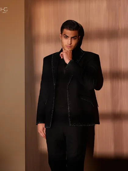 I believe in adding a hint of dazzle with every stitch. This black jacket is edged with a subtle, glittering trim, perfect for catching the light at an evening event.
