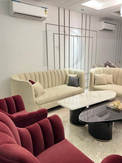 This living room composition features a mix of textures and colors, with channel-tufted sofas in both deep red and neutral beige. The layered coffee tables in black and white marble add a graphic, modern touch.