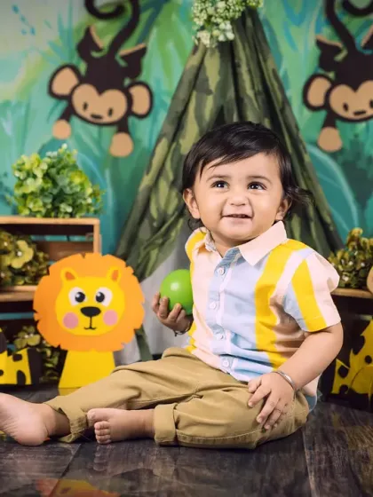 A candid moment of a baby boy playing in his jungle setup, looking off to the side with a happy expression.