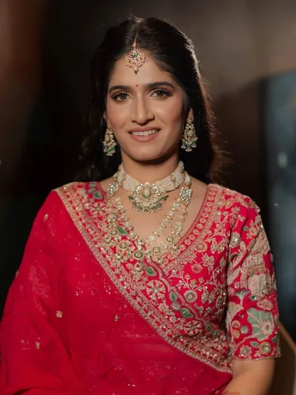 A smiling portrait of the bride in her final look. The makeup is classic and timeless, with a focus on glowing skin and defined eyes.