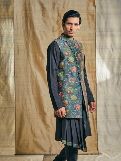 This long pleated jacket kurta, paired with a classic churidar pajama, offers a unique silhouette that is both regal and contemporary.