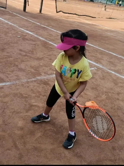 A young player ready to hit the ball. Her stance and focus show that she is ready for the shot.