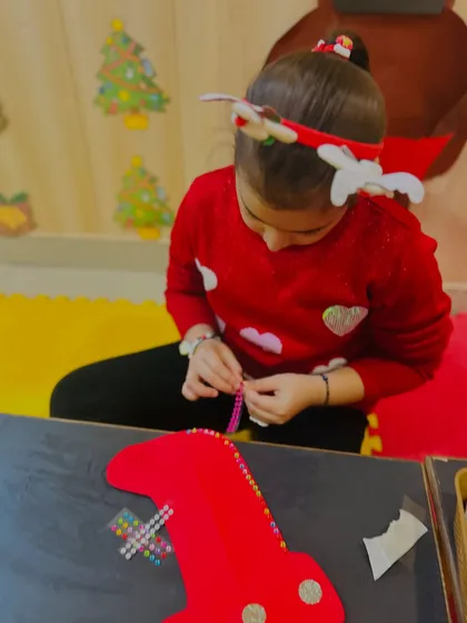 An older student carefully threads beads for her stocking decoration.