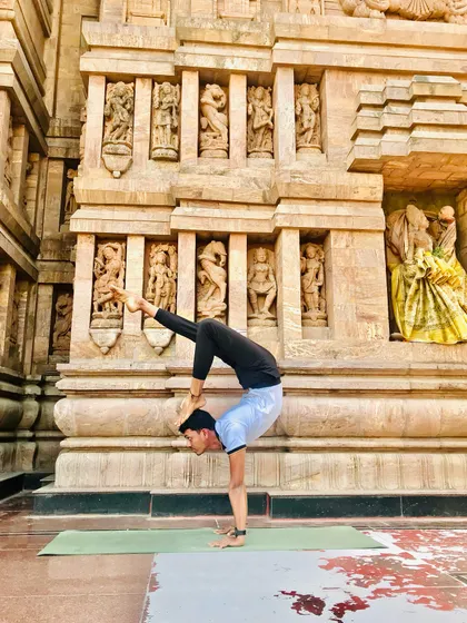 In scorpion pose, touching the foot to the top of the head symbolizes enlightenment. Tapping it there is said to reduce bad qualities. It's a pose rich with meaning and physical challenge.