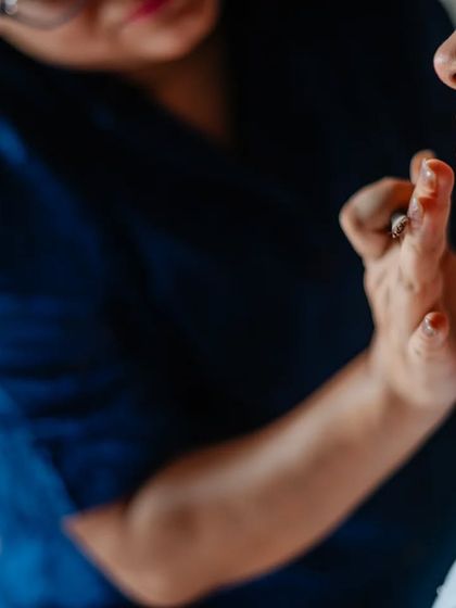 A close-up detail shot of the makeup artist at work, focusing on the hands and the artistry.