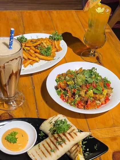 A table full of happiness. This spread includes our grilled wraps, peri peri fries, a fresh salad, and our signature shakes and mocktails.