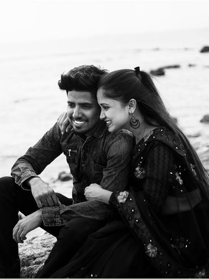 A classic black and white photo of a couple sharing a happy, relaxed moment by the sea. This timeless style is perfect for capturing pure emotion.
