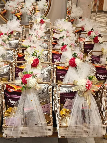 Handling bulk orders without compromising on beauty is my specialty. This image shows a large order of identical return gift hampers, each one carefully assembled and decorated with delicate white netting and floral arrangements, ensuring every guest receives a perfect thank you.