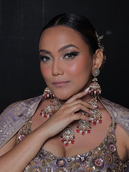 This model wears a beautiful Polki set with red bead accents, which perfectly complements her lavender-grey lehenga.