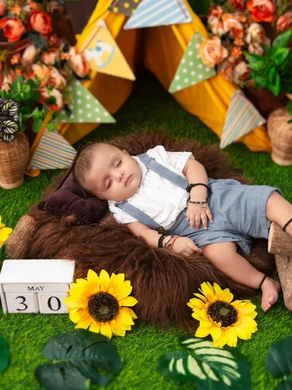 A baby sleeps peacefully in a rustic camping-themed setup, complete with a miniature tent and sunflowers. We design creative and imaginative scenes to make your baby's photoshoot truly one-of-a-kind.