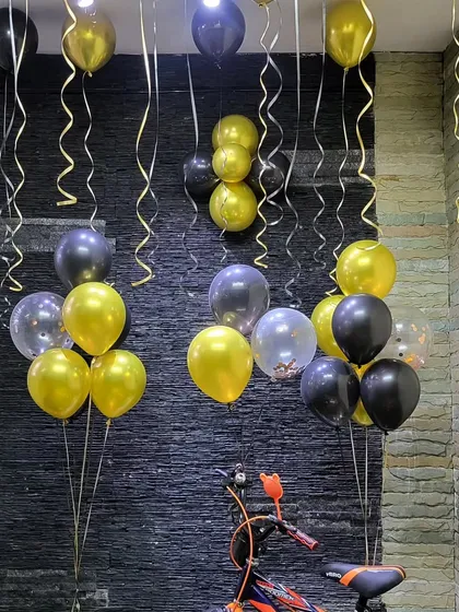Helium balloon bunches in black, gold, and transparent confetti, perfect for decorating a corner of a room.