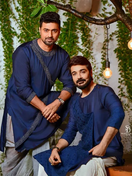A dynamic shot of superstars Prosenjit Chatterjee and Dev Adhikari for an Anandalok cover. Dressed in matching blue kurtas, their camaraderie and star power are the central focus of this image.