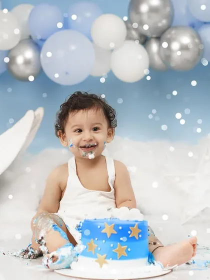 Pure happiness on display as a baby boy with a frosting-covered face smiles during his fun and messy first birthday cake smash.