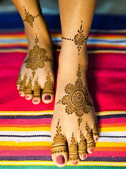 This elegant foot design features a central mandala with a delicate chain connecting to an ankle band.