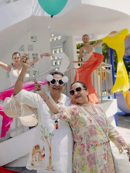 A fun, candid moment of two guests enjoying the welcome festivities, posing with quirky sunglasses and a balloon.