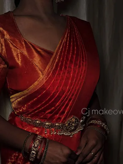 A close-up of the beautiful draping of a traditional red Kanjivaram saree for a bridal look.
