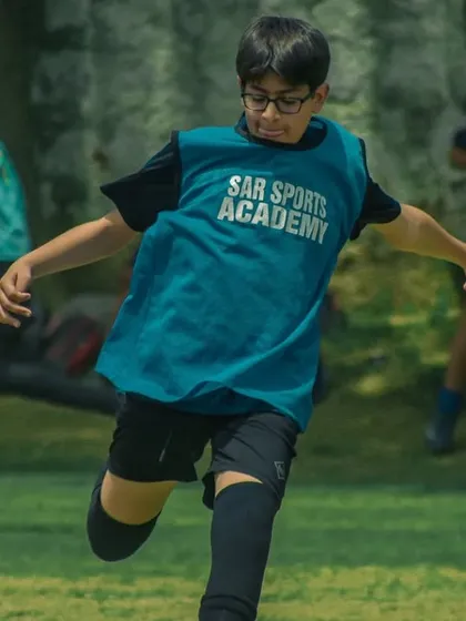 A player in a Sar Sports Academy bib runs to get into position.