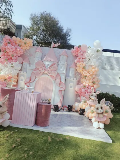 A full view of the magnificent bunny and castle themed party. The outdoor setting allows the grand scale of the castle backdrop and the extensive pastel balloon garlands to truly shine, creating a breathtaking party scene.