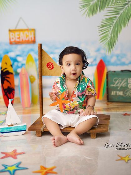 A happy baby enjoying his beach-themed photoshoot, holding a starfish prop. The details in the setup make it feel like a real day at the beach.