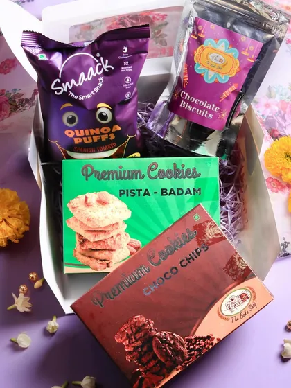 Our 'Joyful Diwali Box' is designed for cookie lovers. It includes our premium Pista Badam and Choco-Chip cookies, along with chocolate biscuits and a pack of savory quinoa puffs for balance.