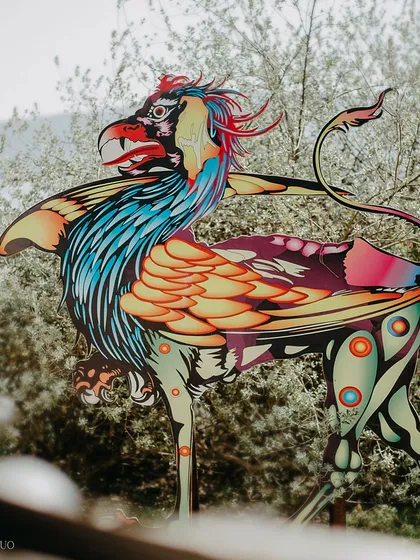 A surreal, colorful griffin-like creature stands as an art installation on the lawns of Udaivilas, bringing the avant-garde festival theme to life.