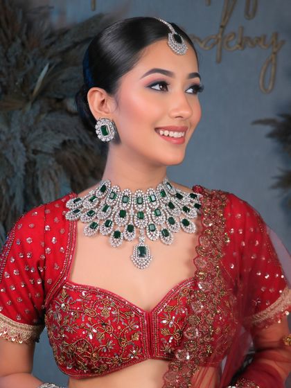 Unveiling bridal elegance that takes your breath away. This look features a clean, sophisticated bun and soft, glowing makeup that complements the diamond and emerald jewelry.